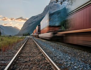 Vivid image of a freight train on tracks beneath majestic mountains in Field, BC.